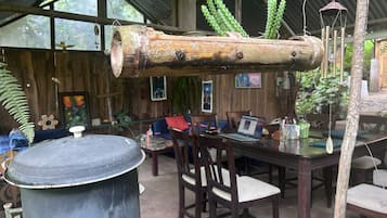 Un interior rústico con un barril de madera grande, una mesa de comedor con sillas y plantas colgantes.