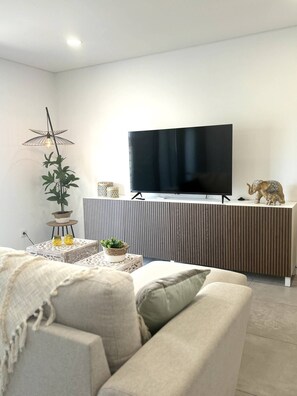 Ein modernes Wohnzimmer mit einem an einer Holzvertäfelung montierten Flachbildfernseher, einer Topfpflanze, Dekoration und einem Sofa.