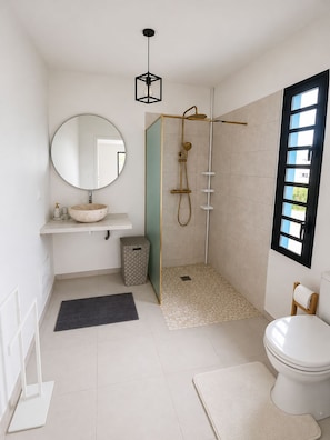 A modern bathroom with a round mirror, a freestanding sink, a shower enclosure, and a toilet. - The Palmier Bleu Duplex! (Rivière-Salée)
