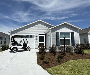 Ein eingeschossiges Haus mit Garage, Auffahrt und Golfwagen davor.