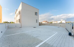 A rooftop terrace with a paved floor, a white building with shutters, and a stone wall. - Gorgeous apartment in Zaton with WiFi (Zaton)