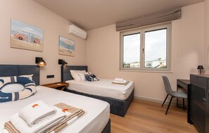 A hotel room with two beds, a desk, a chair, and a window with a view of buildings. - Gorgeous apartment in Zaton with WiFi (Zaton)