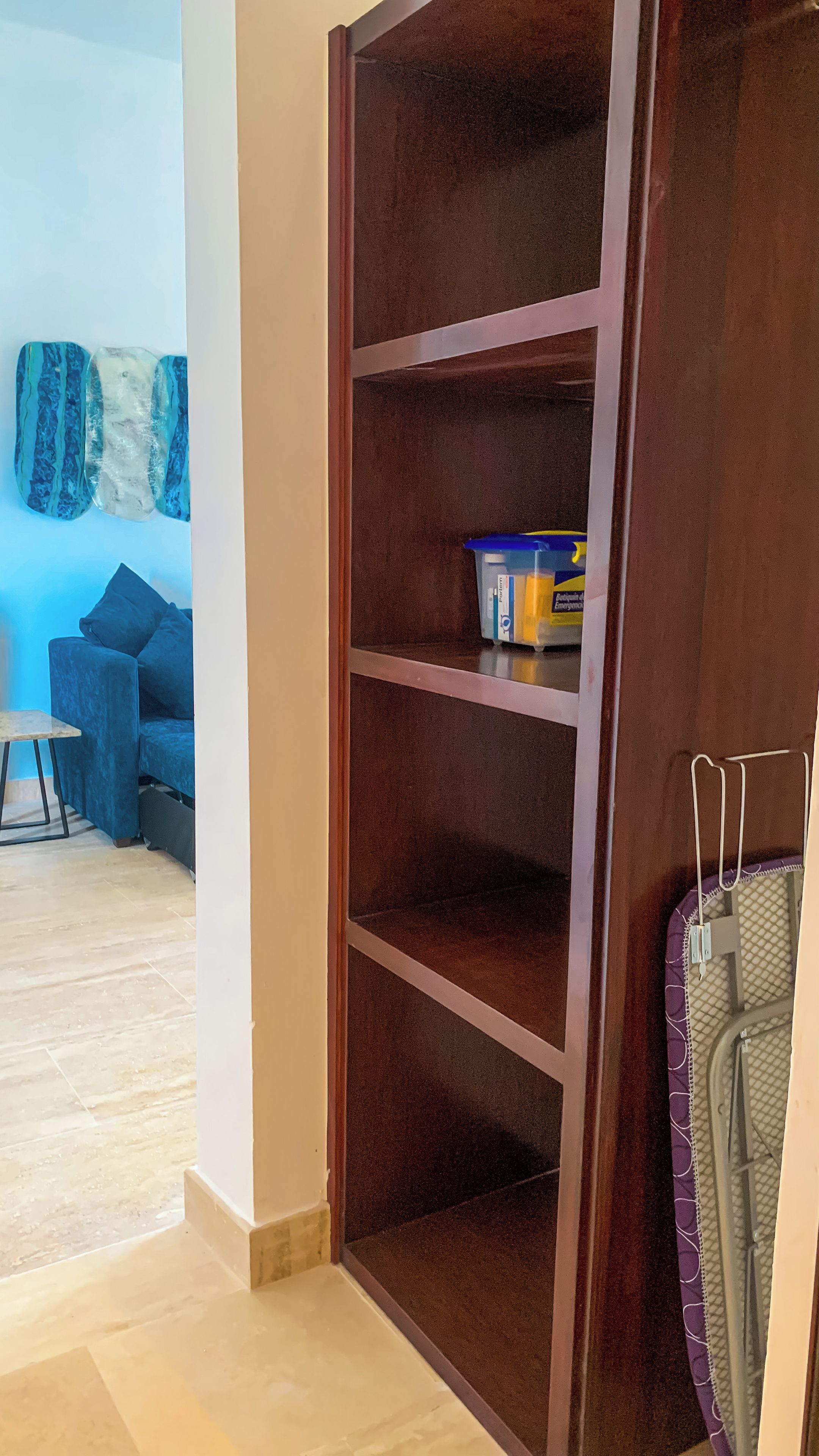 Una habitación con un armario de madera, un sofá azul y una pequeña mesa.