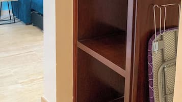 A room with a wooden wardrobe, a blue sofa, and a small table.