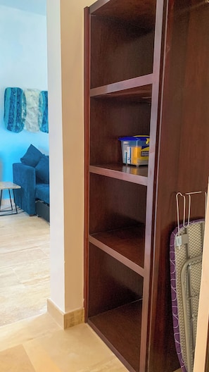 Una habitación con un armario de madera, un sofá azul y una pequeña mesa.