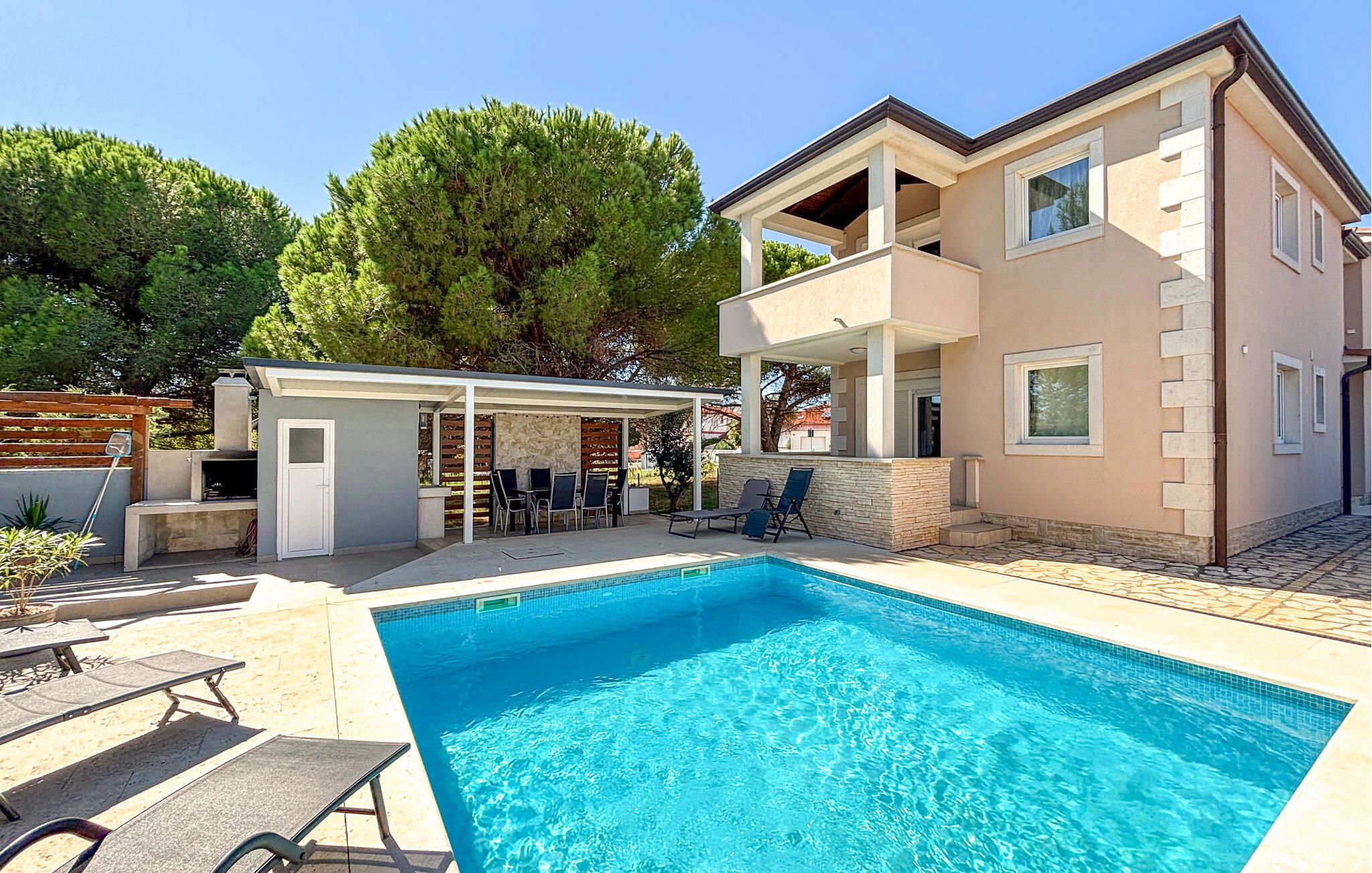 Une maison à deux étages dotée d’une piscine, d’un espace salon extérieur et d’un patio couvert.