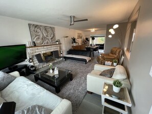 A modern living room with a flat-screen TV, a fireplace, a sofa, a coffee table, and a dining area. - 5 Star 5 Bedroom Delta Home (Clean/Pet Friendly) Min 30 Days + 30% Discount (Delta)