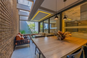 A modern interior with a brick wall, a wooden dining table, and a seating area with a view of greenery outside. - Studio c Piscina e Academia a 400m da Av Paulista (São Paulo)
