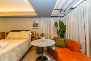 A hotel room with a bed, a sofa, a small table, and a potted plant. - Studio c Piscina e Academia a 400m da Av Paulista (São Paulo)