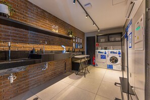 A modern kitchen with a brick wall, stainless steel appliances, and a built-in washing machine. - Studio c Piscina e Academia a 400m da Av Paulista (São Paulo)
