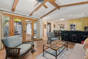 A spacious living area with a wooden ceiling, a glass coffee table, and a dining area with a bar. - Escape to Casita at East Beach! (Santa Barbara)