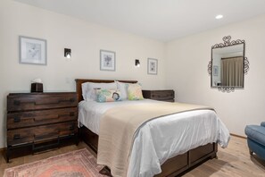 Une chambre à coucher comprenant un lit, une commode, un miroir et des lampes fixées au mur.