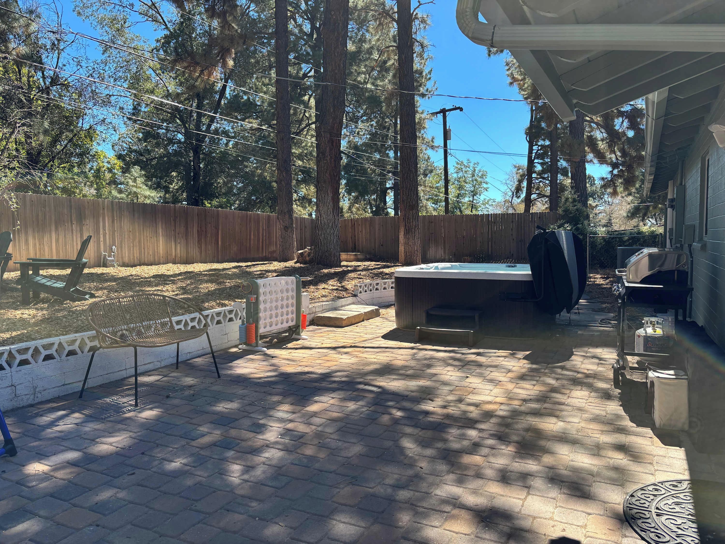 A backyard with a hot tub, outdoor seating, and a wooden fence.