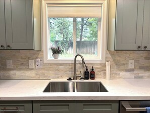 A kitchen with a double sink, a window, and a potted plant. - Remodeled Flagstaff Retreat Hot Tub and Trails (Flagstaff)