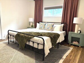 A neatly arranged bedroom with a bed, bedside lamps, a nightstand, and a window with curtains. - Remodeled Flagstaff Retreat Hot Tub and Trails (Flagstaff)