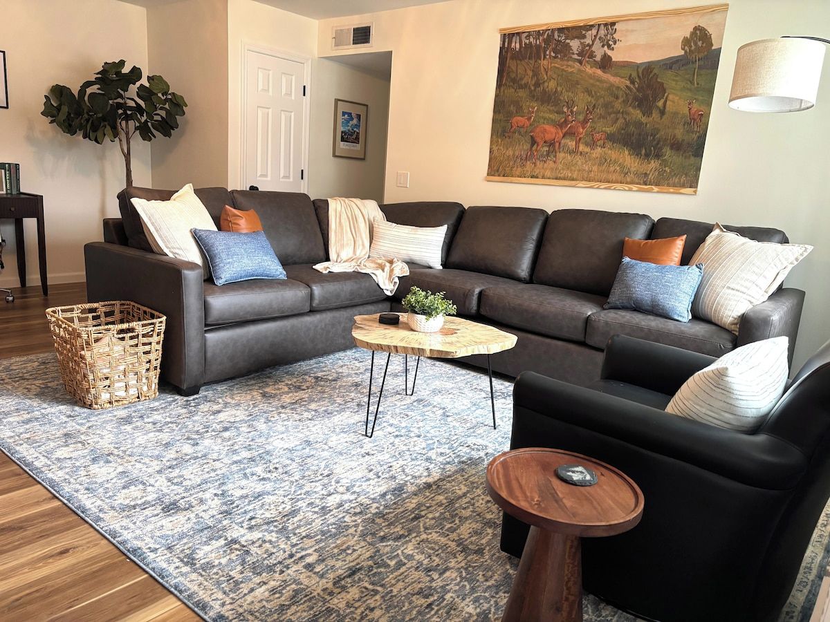 A living room with a sectional sofa, a round coffee table, and a patterned rug.