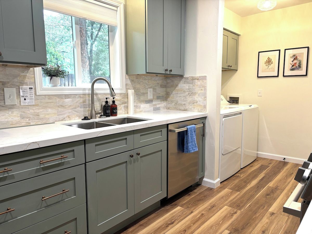 A kitchen with grey cabinets, a stainless steel sink, and a built-in dishwasher.