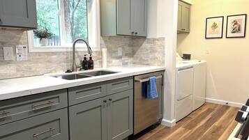 A kitchen with grey cabinets, a stainless steel sink, and a built-in dishwasher.