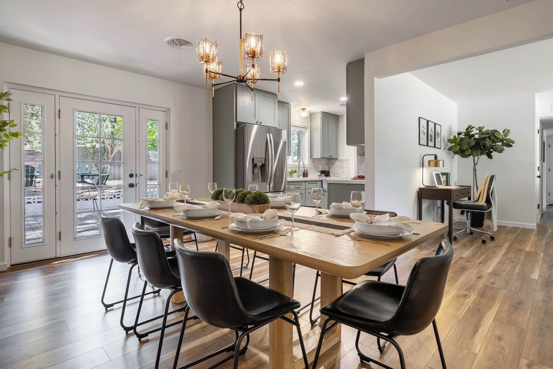 Une cuisine moderne dotée d’un îlot central, d’appareils électroménagers en acier inoxydable et d’un coin repas avec une table en bois et des chaises noires.
