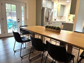 Una cocina moderna con un refrigerador de acero inoxidable, una mesa de comedor de madera y sillas negras.