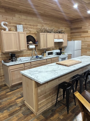 Una cocina moderna con armarios de madera, encimera de mármol y una isla central con taburetes de bar.