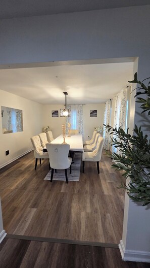 A dining area with a rectangular table, six chairs, and a chandelier. - Crandall Luxe Retreat (Lanham)
