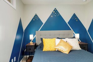 Quarto com cama, duas mesas de cabeceira e cabeceira estampada com estrelas.