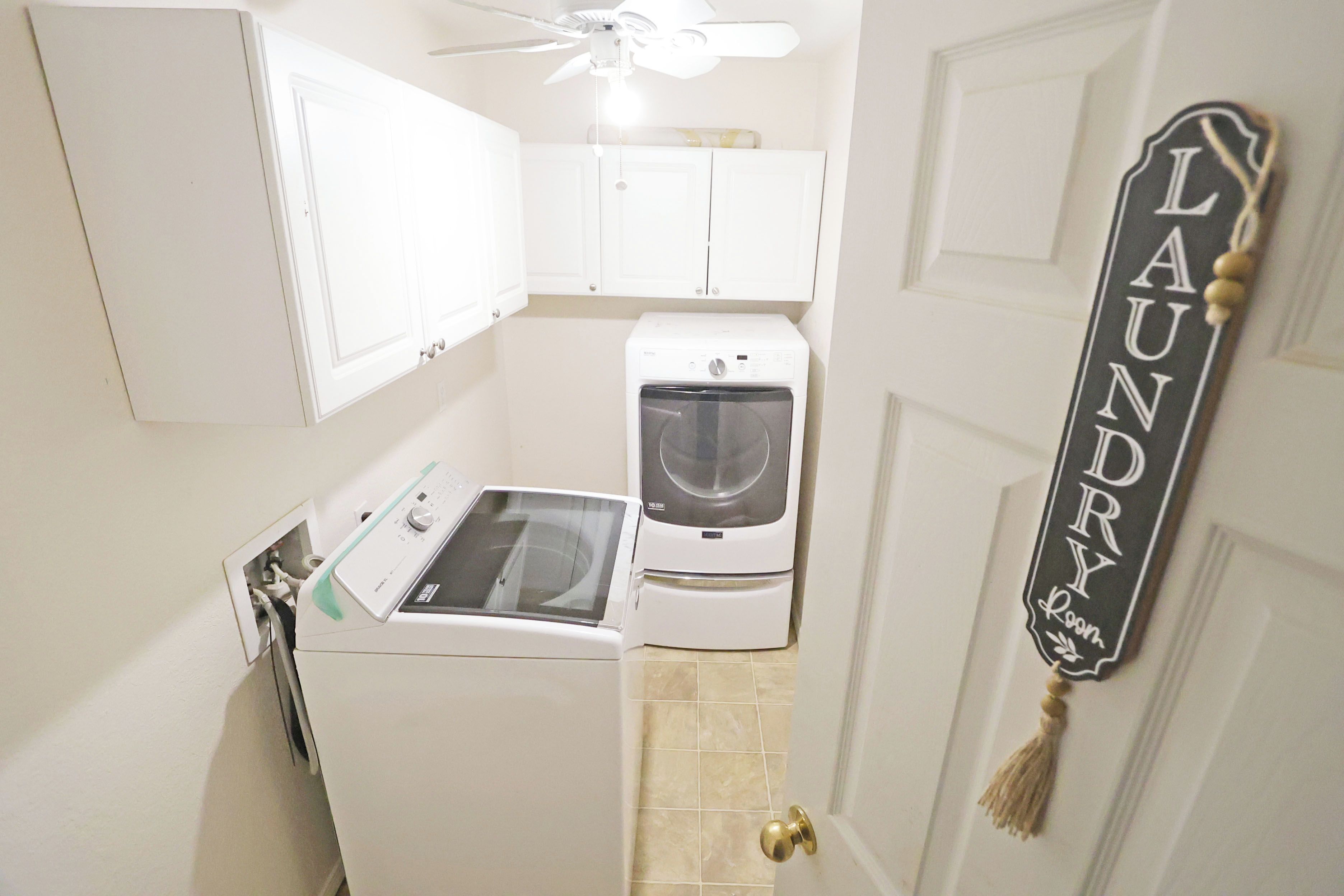A laundry room with a washing machine, dryer, and a ceiling fan.