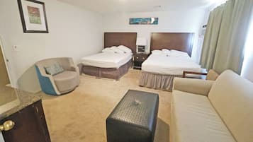 Ett hotellrum med två sängar, en soffa, en fåtölj, ett litet bord och en tavla på väggen.