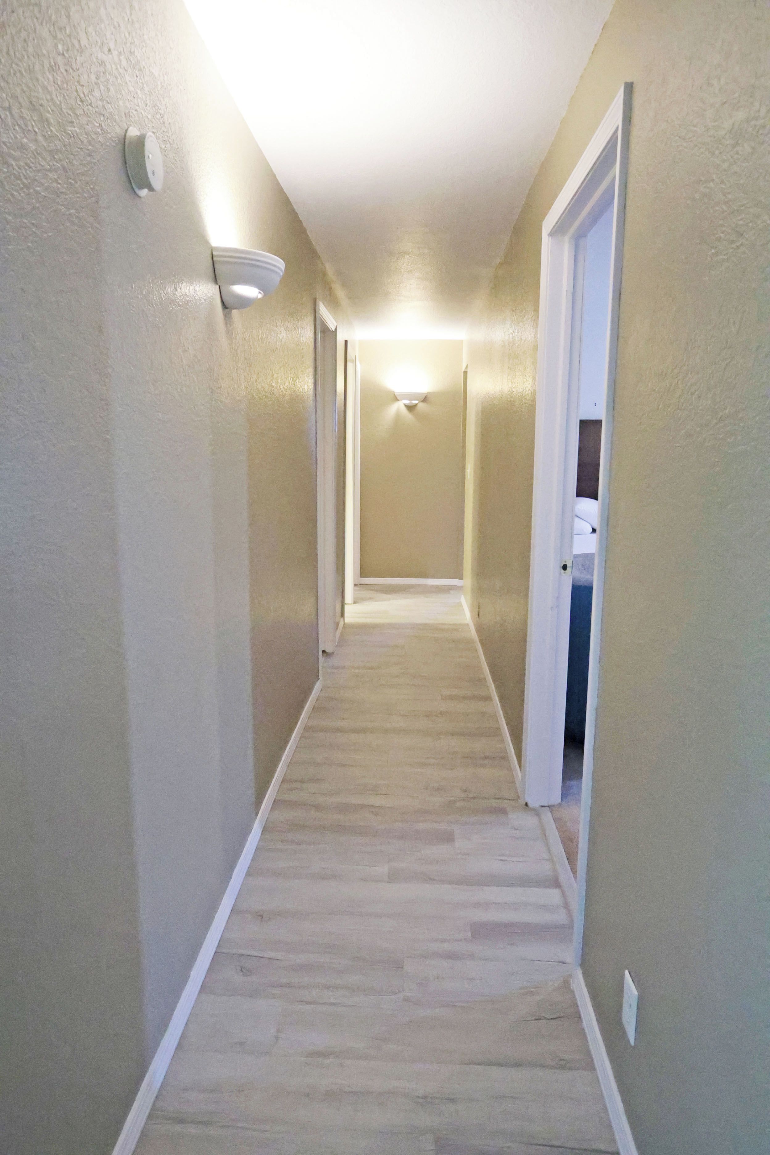 A narrow hallway with carpeted flooring and light-colored walls.