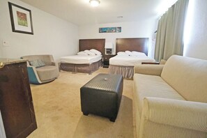 A hotel room with a bed, two sofas, a small table, and a nightstand.