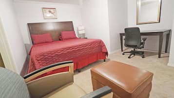A bedroom with a bed, a desk, a chair, and a small table.