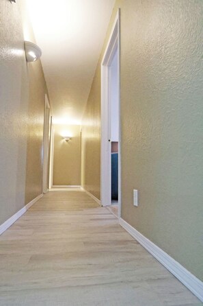 A hallway with a carpeted floor, white trim, and a light fixture on the ceiling.