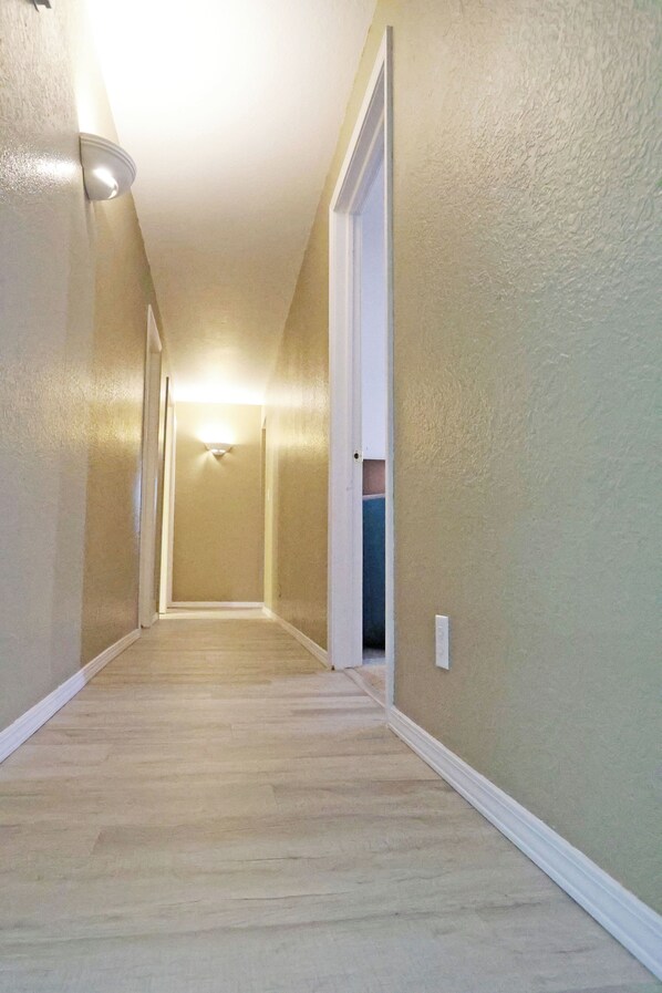 A hallway with a carpeted floor, white trim, and a light fixture on the ceiling.