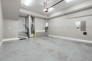 A clean, empty room with a staircase, a fire extinguisher, and a smoke detector on the wall. - Home with Rooftop Patio + Garage, by 12 South and 2 miles to Broadway (Nashville)