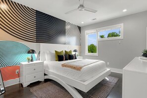 A modern bedroom with a white bed, a nightstand, a desk, a ceiling fan, and a window with a view of trees. - Home with Rooftop Patio + Garage, by 12 South and 2 miles to Broadway (Nashville)
