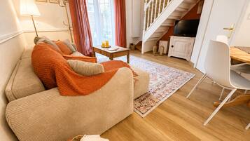 A cozy living room with a sofa, a coffee table, and a dining area with a chair.