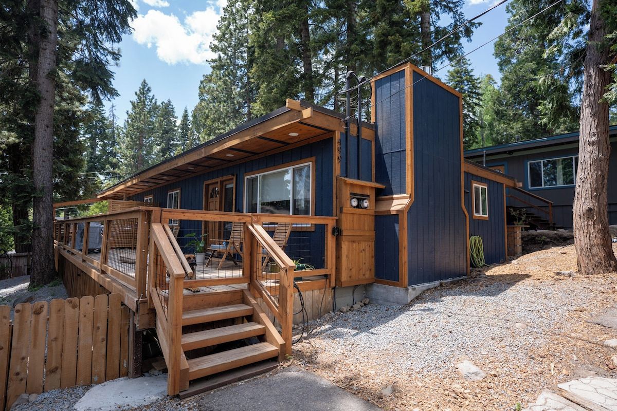 A wooden deck leading to a cabin with a staircase, surrounded by trees.