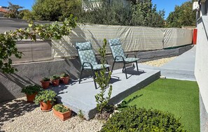 Ein Patio mit Sitzgelegenheiten im Freien, Blumentöpfen und einem kleinen Rasen.