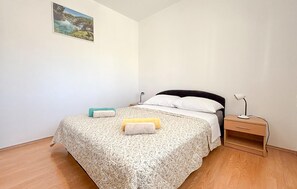 Ein Schlafzimmer mit einem Bett, einem Nachttisch, einer Lampe und einem Bild an der Wand.