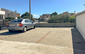 Ein Auto auf einem gepflasterten Einfahrt mit einer Betonmauer und einem Metallzaun im Hintergrund.