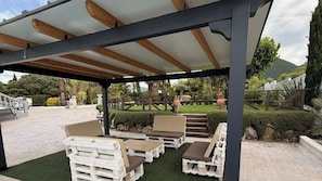 An outdoor patio with wooden furniture and a pergola structure. - Hacienda El Descanso El Bosque by Ruralidays (Cádiz)