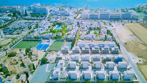 Ein Luftbild eines Küstenresorts mit mehreren Gebäuden, einem Schwimmbad und einem Strand.