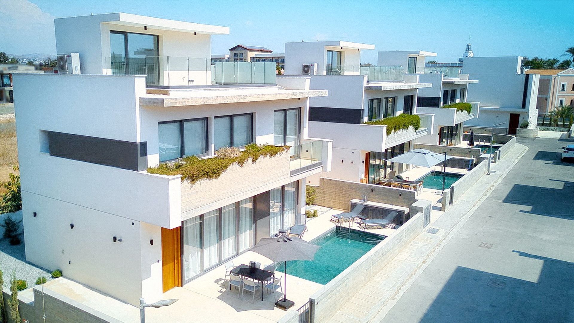 Un immeuble résidentiel moderne doté d’une piscine sur le toit, de balcons agrémentés de plantes et offrant une vue dégagée sur les environs.