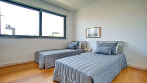 A bedroom with two beds, a window, and a framed picture on the wall.