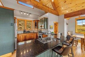 A modern kitchen with granite countertops, stainless steel appliances, and a large island with bar stools. - Willow Lodge, Pet friendly, deck, garage. (Crested Butte)