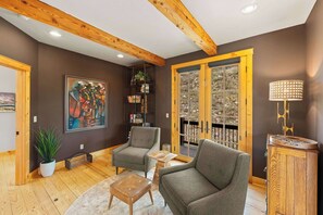 A modern living room with wooden beams, a large window, and a painting on the wall. - Willow Lodge, Pet friendly, deck, garage. (Crested Butte)