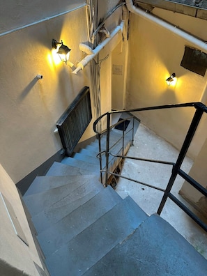 A stairwell with a metal handrail, a radiator, and two wall-mounted light fixtures. - Secret Garden Loft - Private Garden & Hot Tub (Palermo)