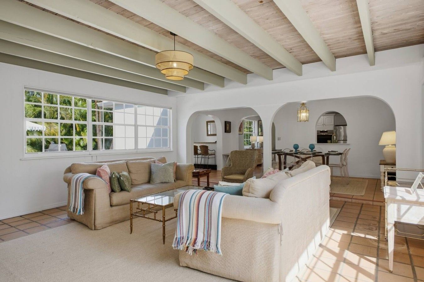 A spacious living area with a sofa set, a coffee table, and a dining area with a table and chairs.