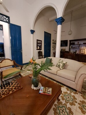 A living room with a sofa, a coffee table, a chessboard, and a vase with flowers. - Hotel Casa Caribe Colonial (Barranquilla)